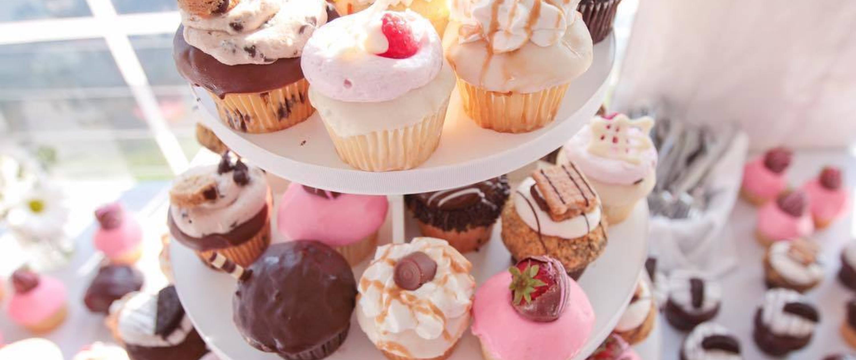 Table and tiered cake stand with an assortment f cupcakes