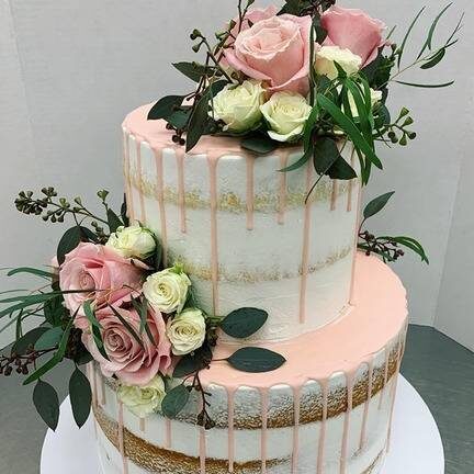 Pretty ppink and gold wedding cake with large flowers on it.